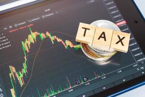 Cryptocurrencies with TAX word and stock chart candlestick on tablets background photo