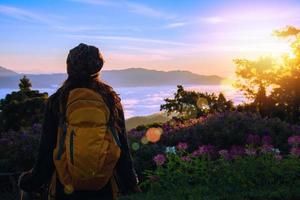 Young woman Tourists with backpacks Standing watching nature beautiful landscape view And fog on the top of the mountain Morning sunrise. photo