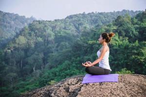 Asian women relax in the holiday. Play if yoga. On the Moutain rock cliff. Nature of mountain forests in Thailand. Young woman practicing yoga in the nature female happiness. exercise yoga photo