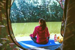 Young woman in the sport wear outfit is sitting and relaxing in the camping in the forest. photo