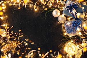 Christmas gift with blue ribbon and Christmas decoration balls on abstract bokeh black background with copy space. Holiday background greeting card for Merry Christmas and New Year.