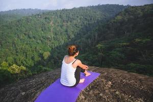 las mujeres asiáticas se relajan en las vacaciones. jugar si yoga. en el acantilado de roca de montaña. naturaleza de los bosques de montaña en Tailandia. mujer joven practicando yoga en la naturaleza felicidad femenina. ejercicio de yoga foto