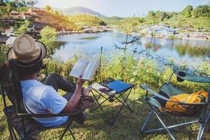 Asian man tourists camping and And working notebook, She is happy, relaxed, enjoying reading a book, Travel nature, Travel relax. photo