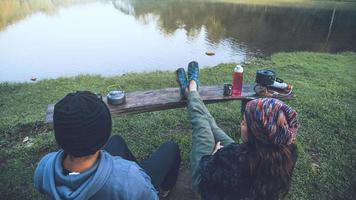 Asian couples feel relaxed and happy with morning drinking coffee by the lake. Couple romantic traveling camping, Honeymoon. photo
