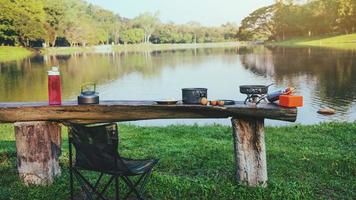 El fondo de la olla y el gas de picnic que se coloca sobre la mesa de madera. acampar, hacer picnic, cocinar, comer junto al lago. foto