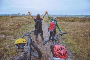 amantes asiáticos mujeres y hombres viajan fotografía naturaleza. viajar relajarse andar en bicicleta en la naturaleza salvaje. pararse en la línea. en el prado en el bosque. tailandia foto