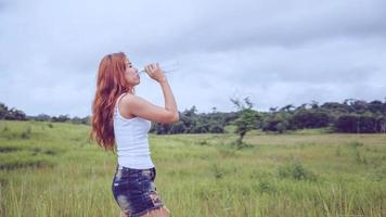 las mujeres asiáticas viajan relajarse en las vacaciones. bebe agua en un prado verde. foto