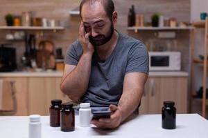 Caucasian man with headache looking at smartphone photo