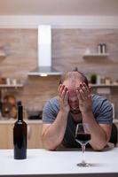 Desperate man feeling miserable while having glass with wine photo