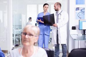 Doctor explaining diagnosis to nurse in waiting area photo