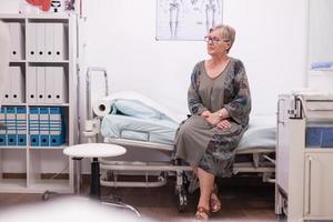 Elderly woman sitting on hospital bed photo