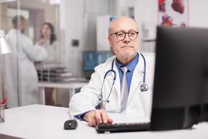 Senior doctor typing expertise rapport photo