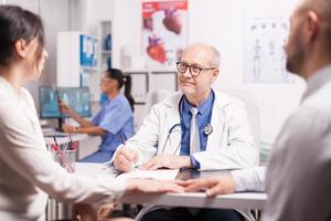 Senior doctor writing notes on clipboard photo