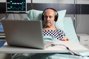 Senior sick man in hospital bed breathing through oxygen mask
