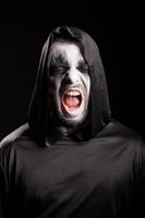 Portrait of grim reaper screaming over black background