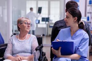 Enfermera médica explicando el diagnóstico a la paciente mayor discapacitada foto