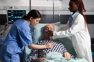 médico africano y asistente médico ayudando al hombre mayor a respirar foto