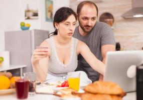 Young couple using laptop at the kitchen