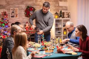 Happy husband pouring red wine to his wife photo