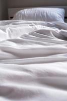 manta blanca arrugada en la cama foto