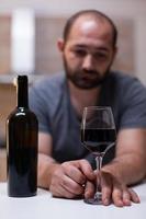 Cerca de vidrio con vino para hombre solitario en la cocina foto