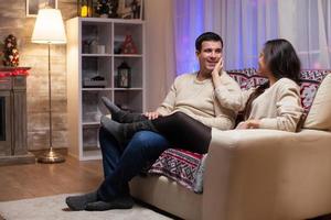 Beautiful young couple sitting on couch celebrating christmas photo