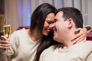 joven esposa y esposo riendo mientras está sentado en el sofá