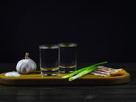 two glasses of cold vodka with onions, garlic, pickled cucumbers and bacon photo