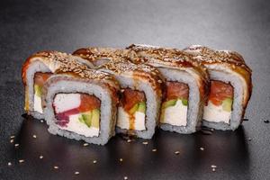 Rollo de sushi fresco delicioso tradicional en un fondo negro foto