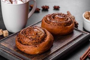 Freshly baked cinnamon roll with spices and cocoa filling on a black background photo