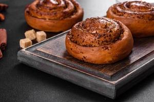 Freshly baked cinnamon roll with spices and cocoa filling on a black background photo
