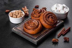 Freshly baked cinnamon roll with spices and cocoa filling on a black background photo