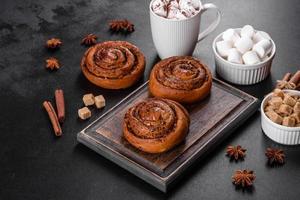 Freshly baked cinnamon roll with spices and cocoa filling on a black background photo