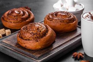 Freshly baked cinnamon roll with spices and cocoa filling on a black background photo