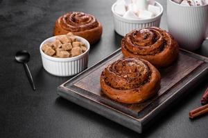 Freshly baked cinnamon roll with spices and cocoa filling on a black background photo
