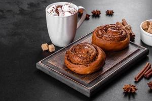 Freshly baked cinnamon roll with spices and cocoa filling on a black background photo