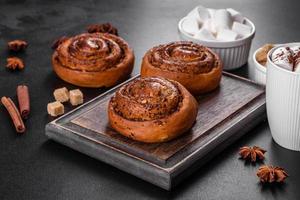 Freshly baked cinnamon roll with spices and cocoa filling on a black background photo