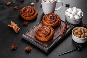 Freshly baked cinnamon roll with spices and cocoa filling on a black background photo