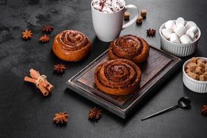 Freshly baked cinnamon roll with spices and cocoa filling on a black background photo