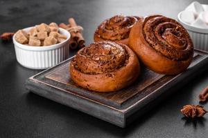 Freshly baked cinnamon roll with spices and cocoa filling on a black background photo