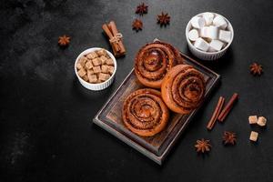 Freshly baked cinnamon roll with spices and cocoa filling on a black background photo