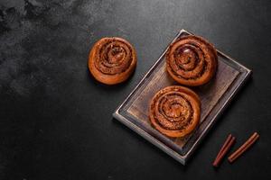 Freshly baked cinnamon roll with spices and cocoa filling on a black background photo