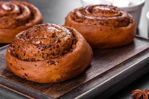 Freshly baked cinnamon roll with spices and cocoa filling on a black background photo