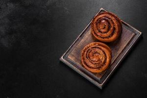 Freshly baked cinnamon roll with spices and cocoa filling on a black background photo