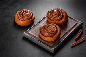 Freshly baked cinnamon roll with spices and cocoa filling on a black background photo