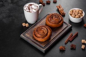 Freshly baked cinnamon roll with spices and cocoa filling on a black background photo