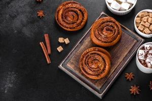 Freshly baked cinnamon roll with spices and cocoa filling on a black background photo