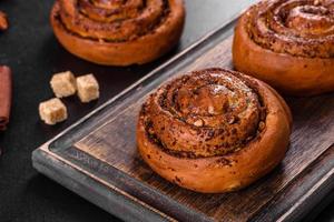Freshly baked cinnamon roll with spices and cocoa filling on a black background photo