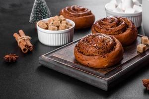 Freshly baked cinnamon roll with spices and cocoa filling on a black background photo
