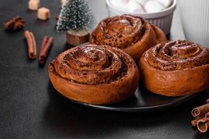 Freshly baked cinnamon roll with spices and cocoa filling on a black background photo